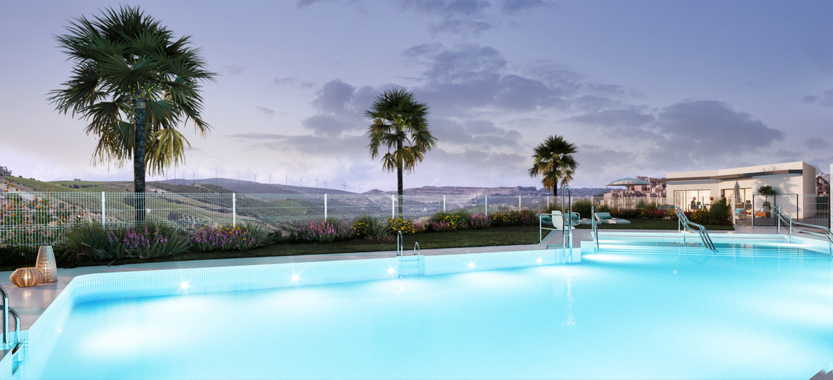 Alonia – Manilva - illuminated outdoor swimming pool at dusk with palm trees and rolling hills backdrop