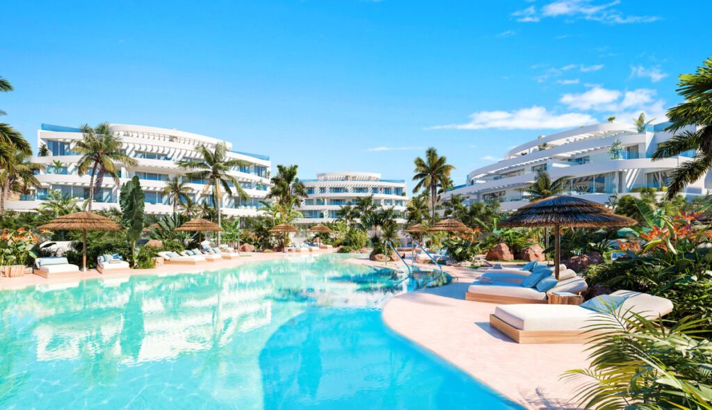 Royal Palms Mijas – FASE IV-1 – La Cala de Mijas - lagoon-style pool surrounded by tropical gardens and white curved residential buildings