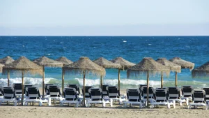 Straw parasols and sun loungers on a sandy Marbella beach with the Mediterranean behind, Costa del Sol