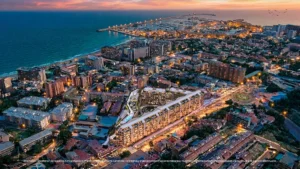 Aerial render of Magna Torremolinos at dusk with La Carihuela beach and Benalmádena Marina along the coast behind